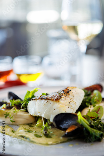 Cod fillet with cauliflower cream, asparagus, clam-wine sauce and mussles. Delicious seafood fish closeup served on a table for lunch in modern cuisine gourmet restaurant
