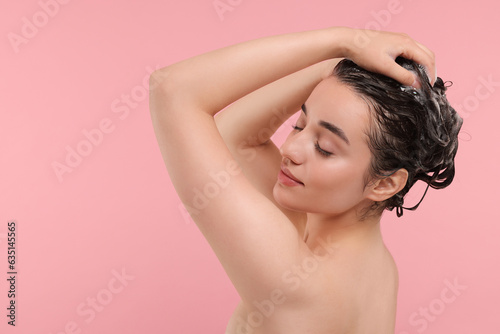Beautiful woman washing hair on pink background. Space for text