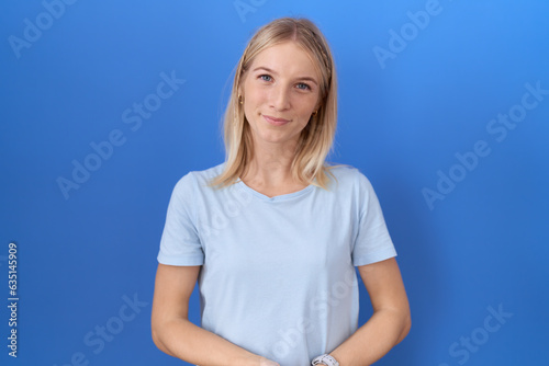 Young caucasian woman wearing casual blue t shirt with hands together and crossed fingers smiling relaxed and cheerful. success and optimistic © Krakenimages.com