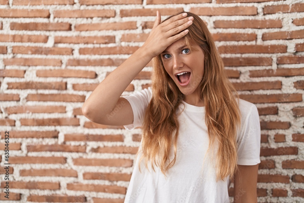 Young caucasian woman standing over bricks wall surprised with hand on head for mistake, remember error. forgot, bad memory concept. Young caucasian woman standing over bricks wall surprised with hand on head for mistake, remember error. forgot, bad memory concept.