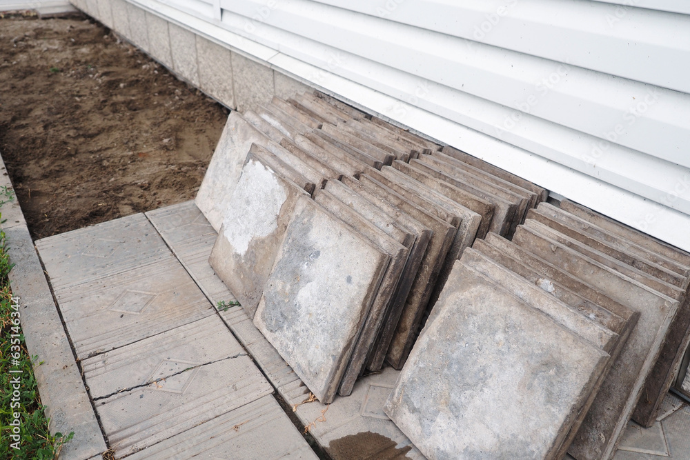 Facing concrete tiles lie on ground in stack. Replacing building foundation. Repair and construction. Background. Facing concrete tiles lie on ground in stack. Replacing building foundation. Repair and construction. Background.