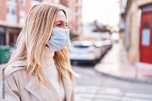 Young blonde woman wearing medical mask standing at street