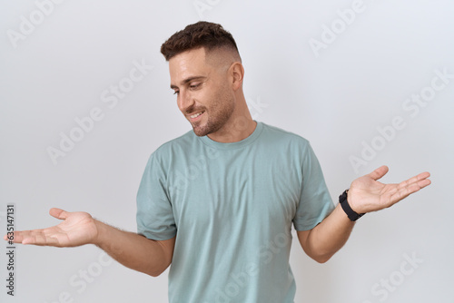 Hispanic man with beard standing over white background smiling showing both hands open palms, presenting and advertising comparison and balance