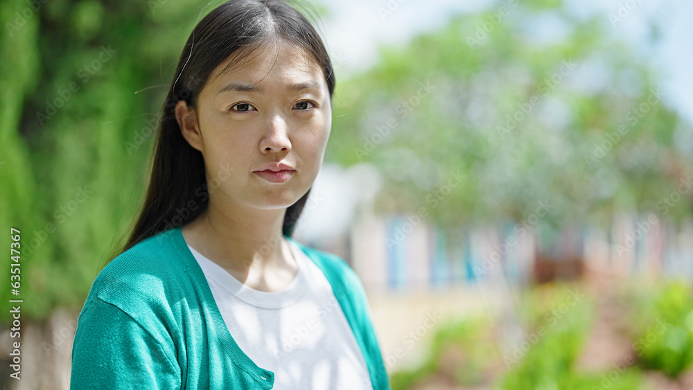 Young chinese woman standing with serious expression at park Young chinese woman standing with serious expression at park