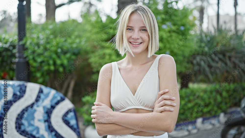 Young blonde woman standing with arms crossed gesture smiling at park Young blonde woman standing with arms crossed gesture smiling at park