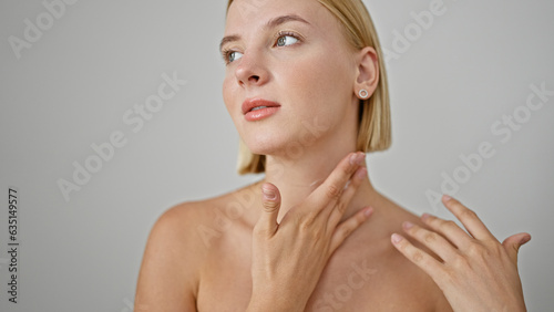 Young blonde woman massaging neck over isolated white background