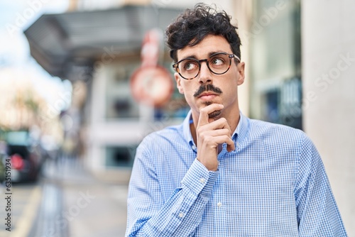 Young caucasian man standing with doubt expression at street