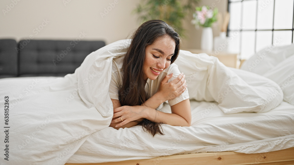 Young beautiful hispanic woman lying on bed covering with bedsheet at bedroom Young beautiful hispanic woman lying on bed covering with bedsheet at bedroom