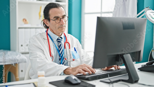 Middle age man doctor using computer at the clinic