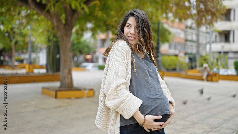Young pregnant woman smiling confident touching belly at park Young pregnant woman smiling confident touching belly at park