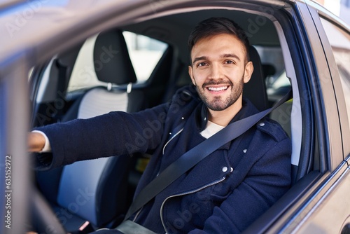 Young hispanic man smiling confident driving car at street © Krakenimages.com