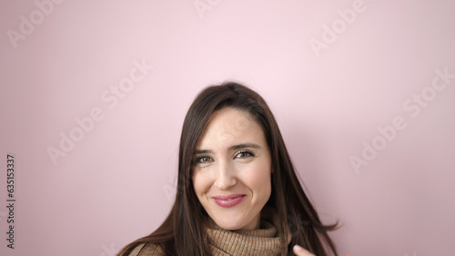 Beautiful hispanic woman smiling confident standing over isolated pink background