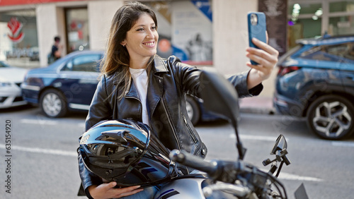 Young blonde woman make selfie by smartphone sitting on motorcycle at street