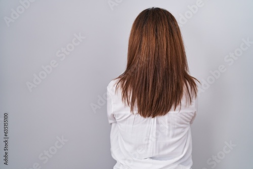 Brunette woman standing over white isolated background standing backwards looking away with crossed arms