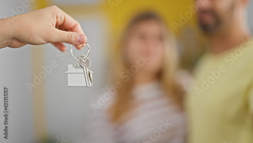 Man and woman couple hugging each other receiving new house keys at new home
