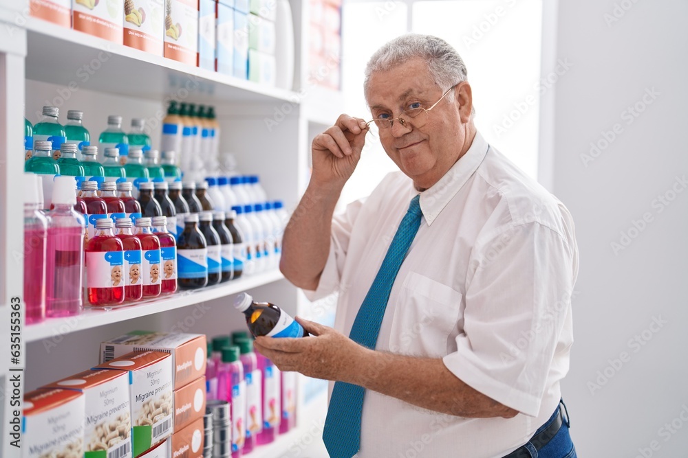 Middle age grey-haired man customer reading medication bottle label at pharmacy