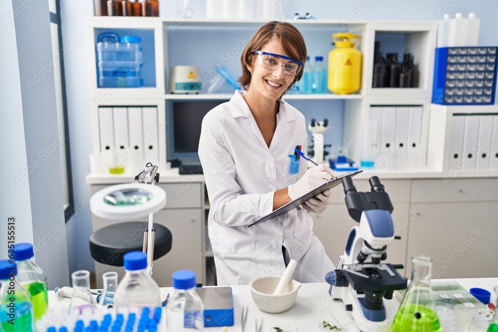 Young beautiful hispanic woman scientist smiling confident writing report working at laboratory Young beautiful hispanic woman scientist smiling confident writing report working at laboratory