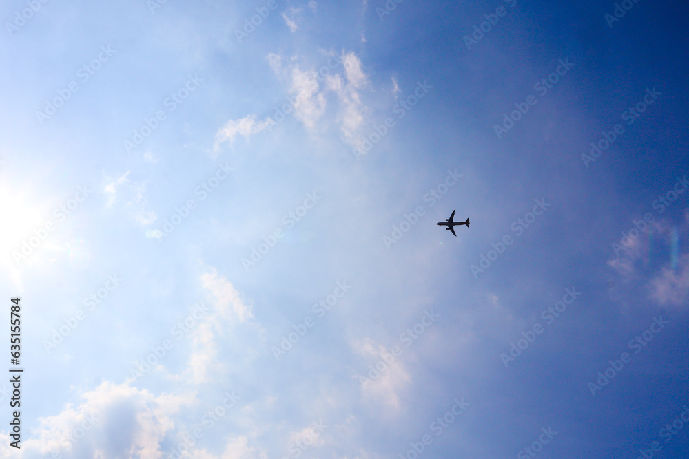 Low-angle shot of an airplane flying under a cloudy blue sky. Symmetrical airplane silhouette photography Low-angle shot of an airplane flying under a cloudy blue sky. Symmetrical airplane silhouette photography