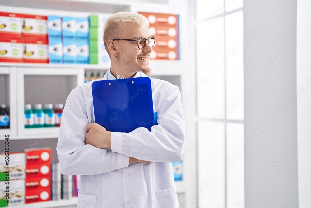Young caucasian man pharmacist smiling confident holding clipboard at pharmacy