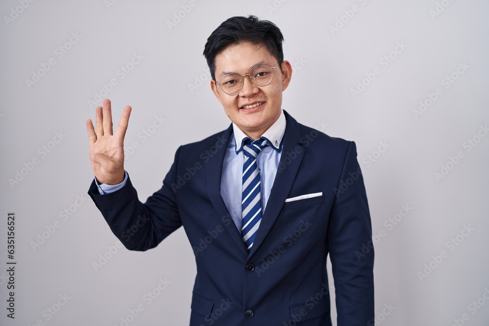 Young asian man wearing business suit and tie showing and pointing up with fingers number four while smiling confident and happy. Young asian man wearing business suit and tie showing and pointing up with fingers number four while smiling confident and happy.