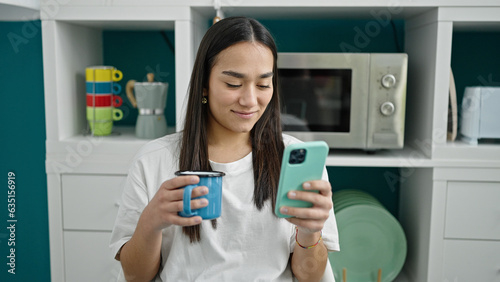 Young beautiful hispanic woman using smartphone drinking coffee at dinning room