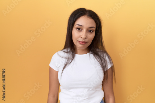 Young arab woman wearing casual white t shirt over yellow background looking sleepy and tired, exhausted for fatigue and hangover, lazy eyes in the morning. © Krakenimages.com