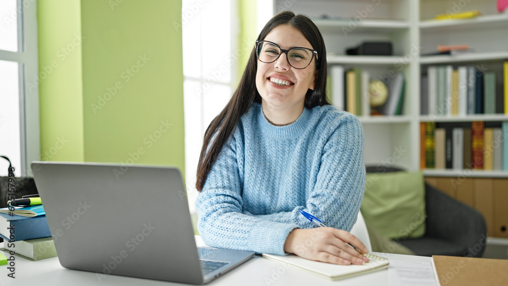 Young hispanic woman student using computer taking notes at library university Young hispanic woman student using computer taking notes at library university