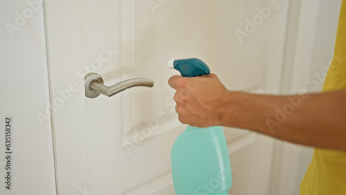 Young hispanic man cleaning door at home
