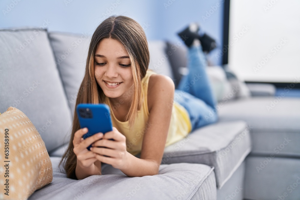 Adorable girl using smartphone lying on sofa at home Adorable girl using smartphone lying on sofa at home