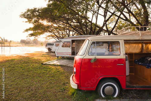 Fototapeta Retro camper van parked in campground on lakeside in the sunset