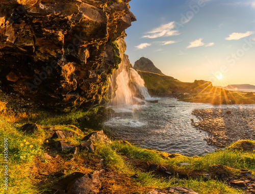 Sunrise over volcanic Kirkjufell mountain with waterfall flowing in summer at Iceland