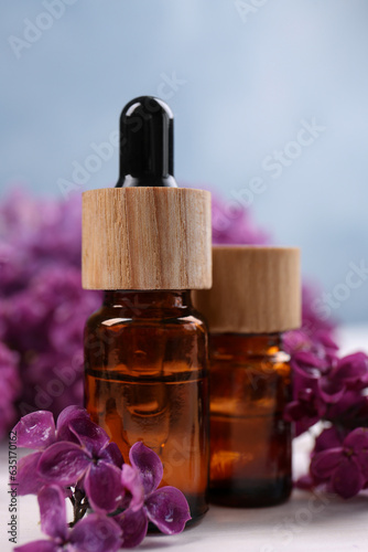 Cosmetic products and lilac flowers on white wooden table  closeup