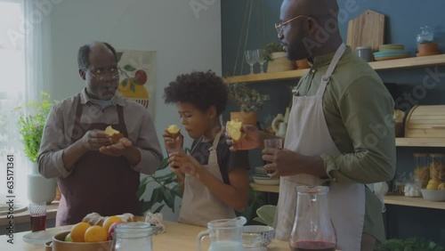 Multi-generational black family eating Meskouta cake and enjoying its taste while cooking traditional North African food at home photo