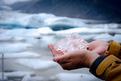 Woman's hand holding ice cubes from the melting of glaciers and floated in the lake Melt from large ice cubes to small ones.