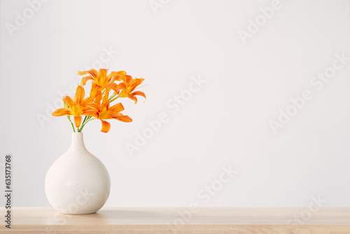 summer flowers in white modern vase on wooden shelf