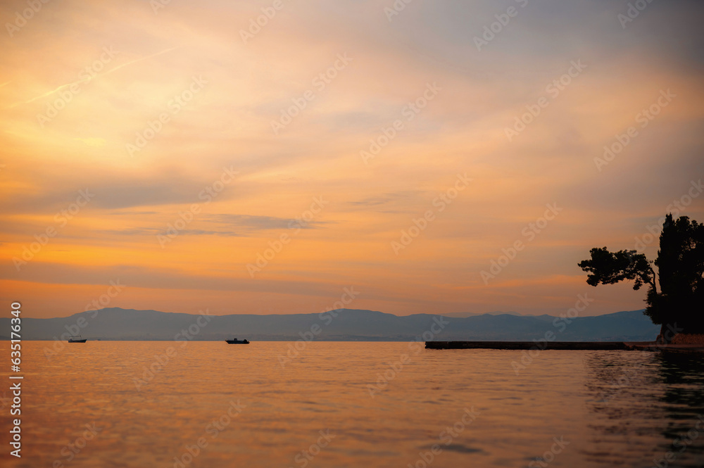 Amazing sunset and boats floating on calm sea
