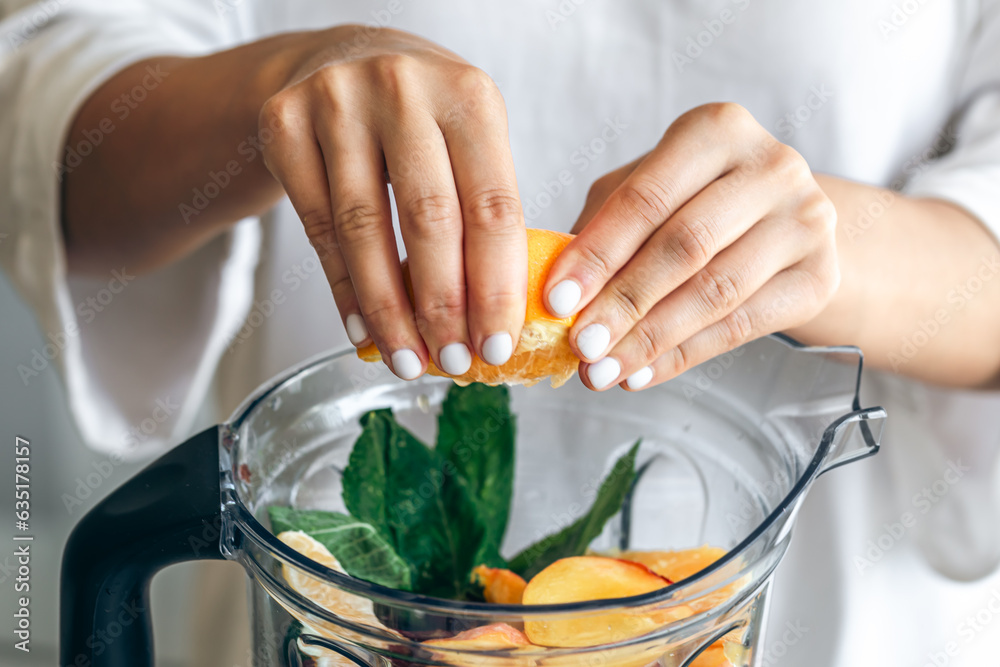 A woman squeezes orange juice into a blender, making a fruit smoothie. A woman squeezes orange juice into a blender, making a fruit smoothie.