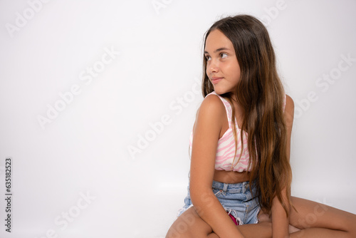 young 11 year old girl sit on floor rest with a smile into camera with copy space isolated on white
