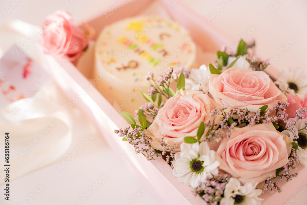 Cake with blooming roses in a pink gift box on a white background.