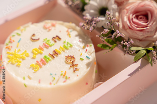 Cake with an inscription with blooming roses in pink gift box.