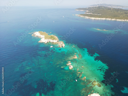 Captured from the sky, a drone showcases Greece's azure waters kissing sun-kissed shores, framing an idyllic Mediterranean mosaic.