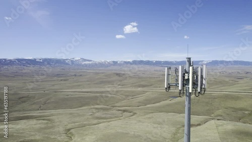 Cinematic drone shot flying backwards to reveal the 4G/5G antenna array at the top of a cell phone tower mast over a rural landscape (Aerial 4K HDR ProRes)