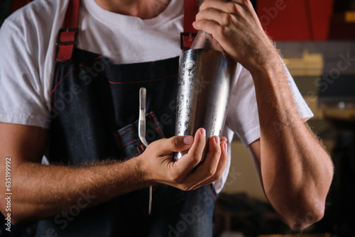 Unrecognizable barman preparing cocktail in cobbler shaker