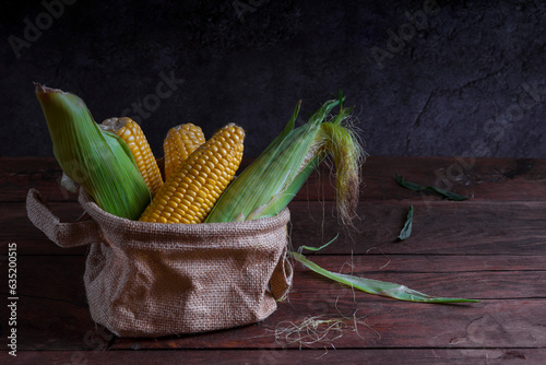 Raw yellow corn on a dark wooden background.