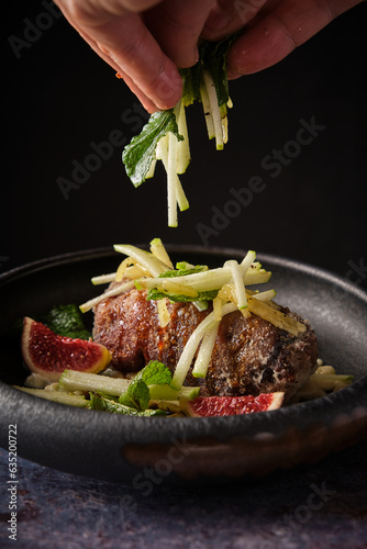 Crop person adding chopped veggies to pig trotter