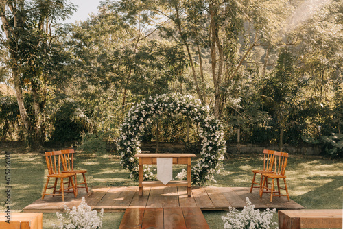 outdoor wedding ceremony with wooden benches and flower arch