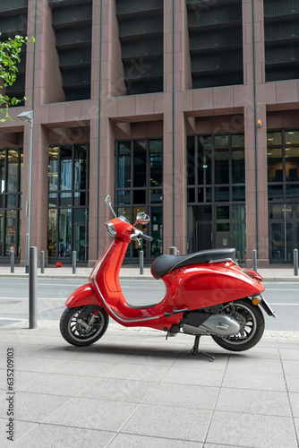 Red vintage scooter parked on a sidewalk. The moped is parked on the sidewalk in the business center of Frankfurt am Main.