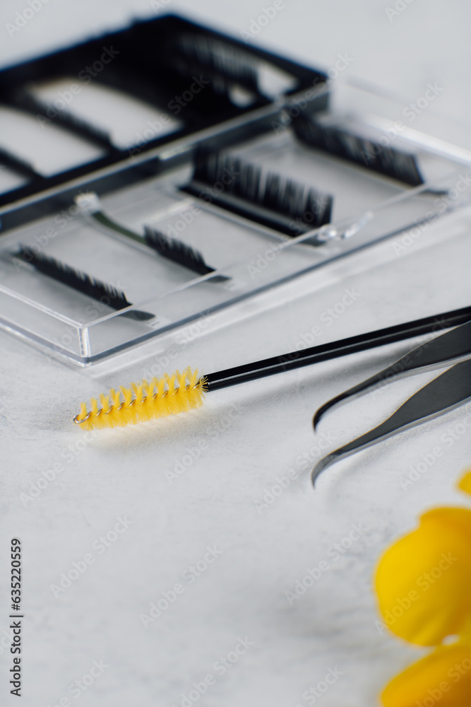 Palette of artificial lashes, disposable brush and isolated tweezers, using for eyelash extension lying on table. Palette of artificial lashes, disposable brush and isolated tweezers, using for eyelash extension lying on table.
