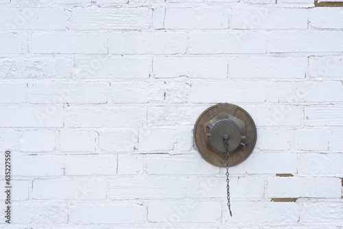 Fire service connection.  Auto sprinkler connection.  FDC or fire department connection.  Standpipe connection on exterior surface of a peeling, white painted brick wall. photo