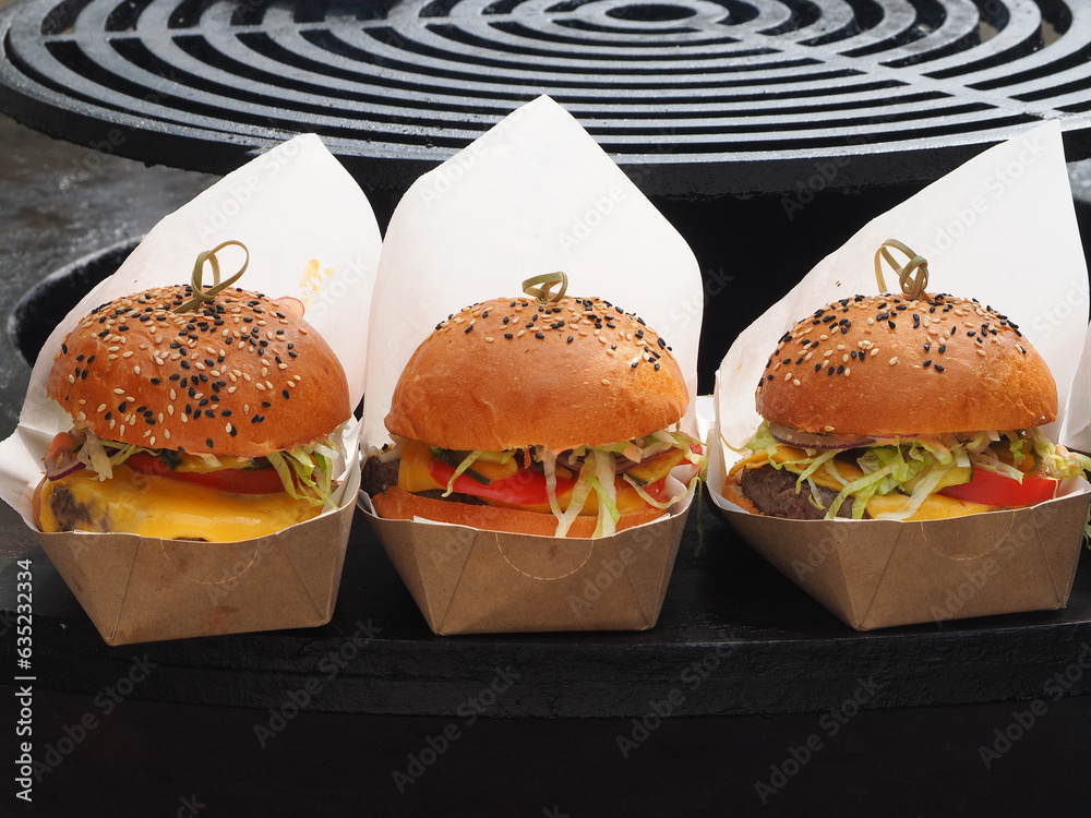 Burgers in cardboard boxes with cheese and herbs, close-up. Natural products, fast food concept.